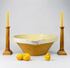 Antique XL French terracotta tian bowl held to demonstrate its substantial scale, with a broad open mouth, deep conical basin, pale cream-yellow glazed interior, and worn rim exposing warm red clay beneath. This Provence pottery piece has the sculptural size and aged surface sought for farmhouse decor, French country decor, and Mediterranean decor.