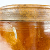 Early 20th-century French provincial confit pot in heavy brown glazed stoneware, complete with a fitted circular lid and two applied handles. Ribbed throwing lines around the lid and shoulder emphasise its handmade construction, while the pale interior glaze supports its original storage function. This antique crock brings aged pottery texture to farmhouse decor, Mediterranean decor, or cottage decor.