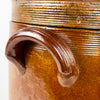 Large antique French confit pot with its original fitted lid, made in early 20th century brown glazed stoneware with a tall cylindrical body, twin pierced ear handles, and horizontal wheel-thrown ridges around the neck. This substantial decorative crock suits French kitchen decor, farmhouse decor, or styling with dried branches as a sculptural pottery vessel.