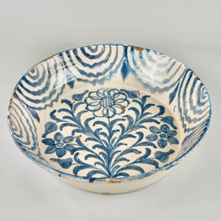 Close-up of central flower design in deep blue on hand-painted Fajalauza lebrillo, surrounded by leafy scrolls, a hallmark of traditional Granada ceramic craftsmanship dating to mid-20th century.