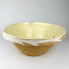 Large antique French tian bowl held from the side, showing the heavy conical profile, broad flared rim, unglazed ochre lower body, and pale glazed upper section. The substantial provincial terracotta form, pouring notch, and age-worn surface make this early 1900s Provence pottery especially effective as farmhouse decor or a sculptural centerpiece bowl.