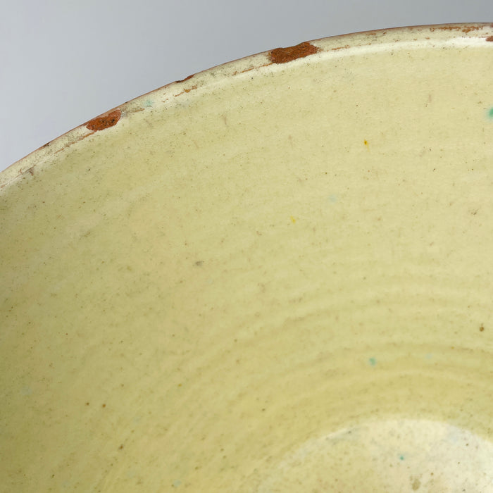 Upper rim detail of an antique French terracotta tian bowl showing the transition between pale yellow glaze, worn light-colored exterior coating, and exposed warm clay. Chips and abrasions remain visible rather than restored, highlighting the bowl’s age and material construction and giving this Provence pottery a tactile French country and farmhouse decor presence.