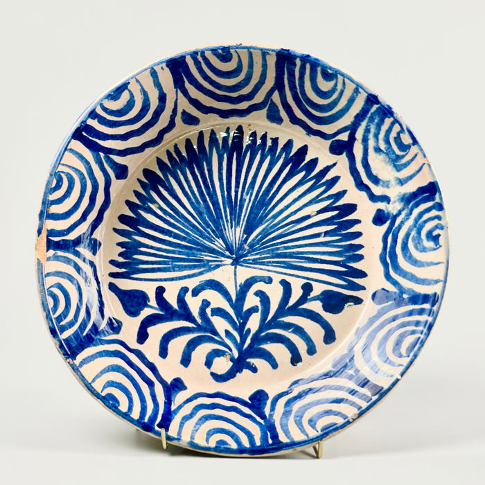 Antique Spanish Fajalauza lebrillo bowl from Granada featuring a cobalt hand-painted palm tree in the center and rhythmic wave motifs around the rim, photographed from the front to showcase its full decorative surface and historic Andalusian ceramic design.