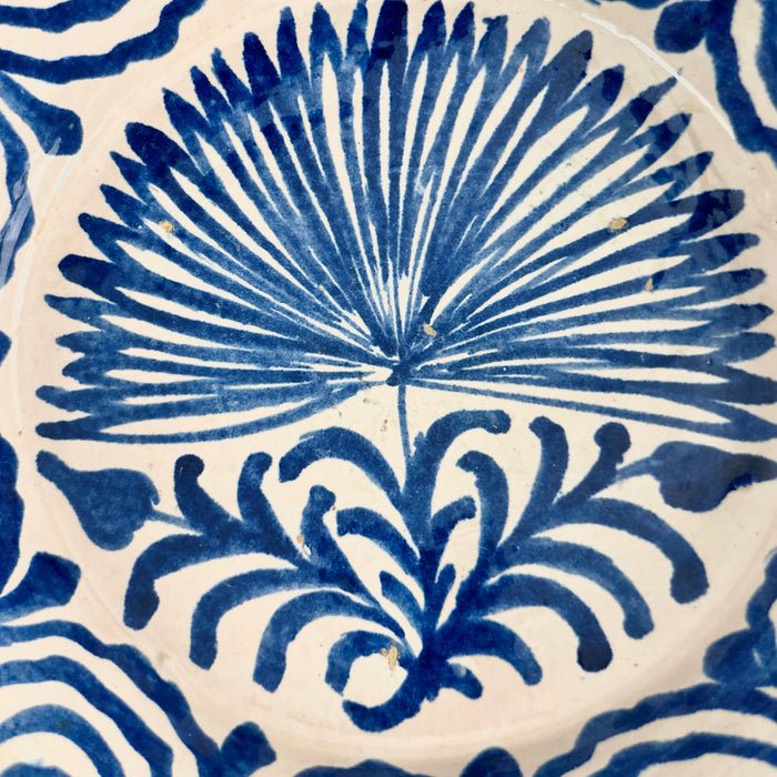 close-up of the palm motif’s central leaves and fronds painted in rich cobalt blue, showing the glaze texture and brushstroke variation achieved by the artisan potter in this 19th-century ceramic piece.