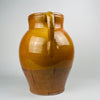 Spanish glazed terracotta olive jar in a two handle form, traditional earthenware vessel with rolled rim and visible throwing rings. The glossy amber glaze shows kiln variation and pooling, while the unglazed terracotta base shows authentic wear and surface rub, ideal for rustic home decor and farmhouse decor styling.