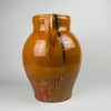 Large antique Spanish terracotta jar with twin handles and a wide mouth, finished in honey brown glaze over terracotta with a clear glaze line and drip trails. The surface patina, firing specks, and handmade form support its use as a floor vase or decorative storage jar in Mediterranean decor interiors.