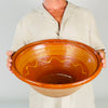 antique French terracotta tian bowl displays pale buff clay, horizontal throwing rings, minor scuffs, and irregularities from handmade production. A deep amber glaze covers the interior and upper rim, creating a rich contrast appropriate for French country decor, farmhouse decor, and collected antique pottery displays.