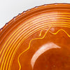 Natural scratches, small firing specks, tonal changes, and soft wear are visible across the glazed well of this early 20th century French tian bowl. Yellow linear decoration frames the warm terracotta interior, while the substantial scale and aged finish support its use as antique pottery decor, a low sculptural vessel, or a farmhouse centerpiece.