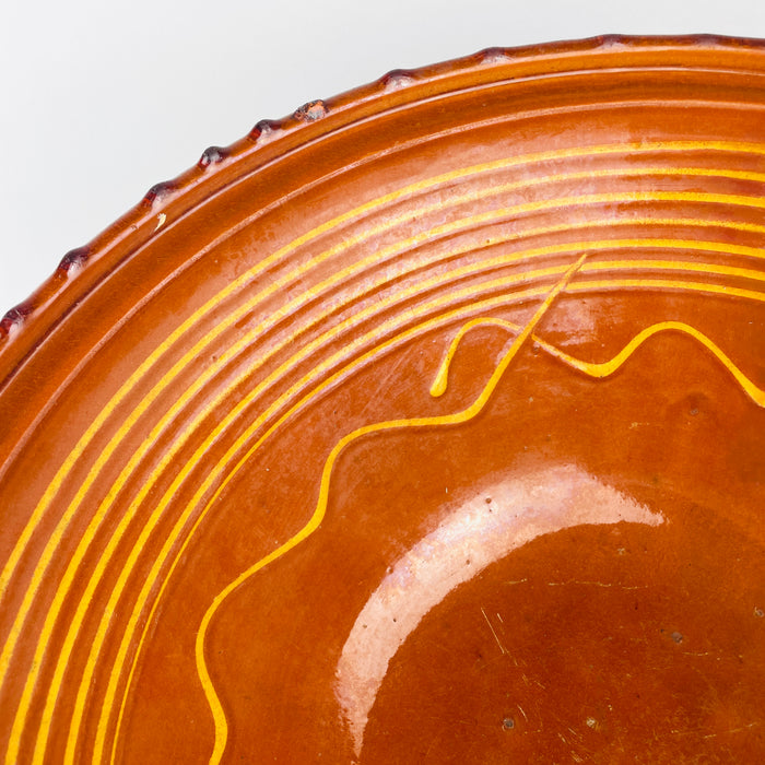Natural scratches, small firing specks, tonal changes, and soft wear are visible across the glazed well of this early 20th century French tian bowl. Yellow linear decoration frames the warm terracotta interior, while the substantial scale and aged finish support its use as antique pottery decor, a low sculptural vessel, or a farmhouse centerpiece.