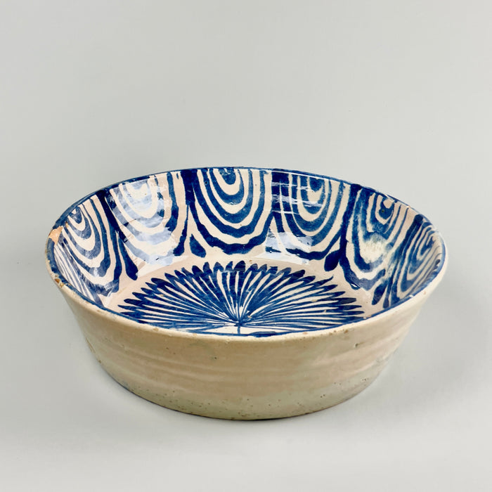 Full top-down view of a 19th-century Spanish ceramic bowl with traditional hand-painted cobalt palm tree and wave decorations, wheel-thrown from earthenware and finished with white glaze, embodying the regional folk artistry of Granada.