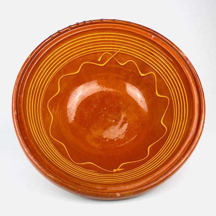 Rich orange and honey brown glaze fills the deep interior of this XL antique French terracotta tian bowl, framed by yellow concentric lines and an expressive wavy motif. The generous open form, handmade irregularities, and aged surface make it a strong decorative bowl for farmhouse decor, rustic home decor, or Mediterranean decor.