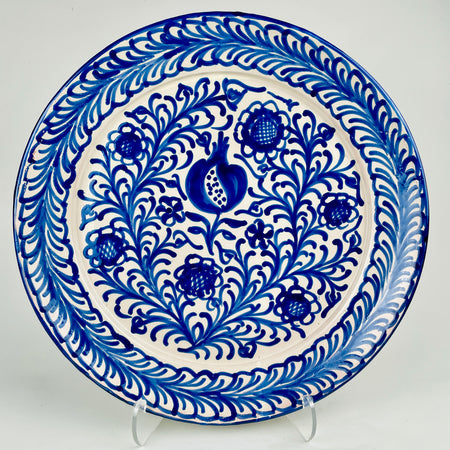 Large Spanish Fajalauza style serving platter in hand painted ceramic with a central pomegranate motif, cobalt blue floral scrolls, and a wide blue leaf border over a white glazed ground. This contemporary artisan platter measures 44.5 cm and works as a wall hanging ceramic plate, centerpiece platter, or Mediterranean decor accent.