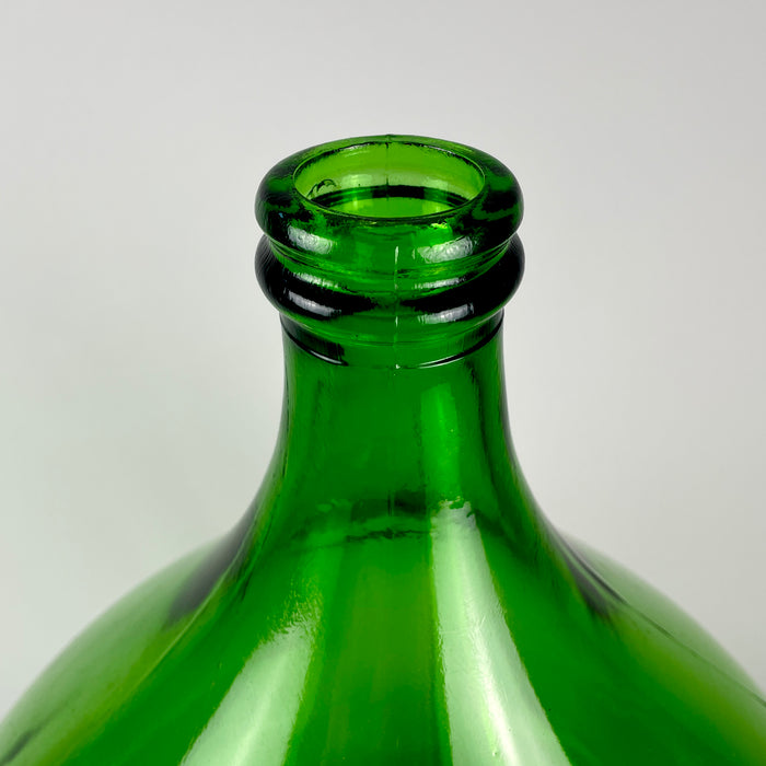Vintage French demijohn made from richly colored emerald-green glass, with a substantial rounded body, sloping shoulders, narrow neck, and thick reinforced rim. Originally used as a large wine carboy, the 25 L vessel can now be displayed empty or used as a branch vase beside a console, fireplace, staircase, or large window.