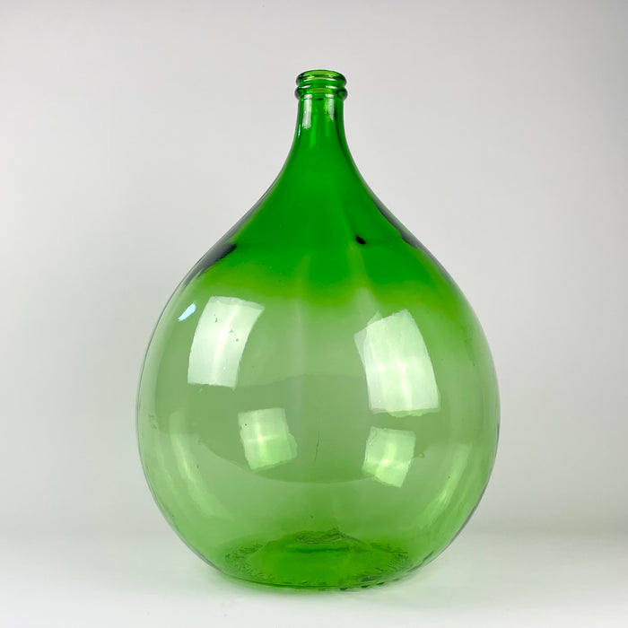 Vintage French demijohn made from richly colored emerald-green glass, with a substantial rounded body, sloping shoulders, narrow neck, and thick reinforced rim. Originally used as a large wine carboy, the 25 L vessel can now be displayed empty or used as a branch vase beside a console, fireplace, staircase, or large window.