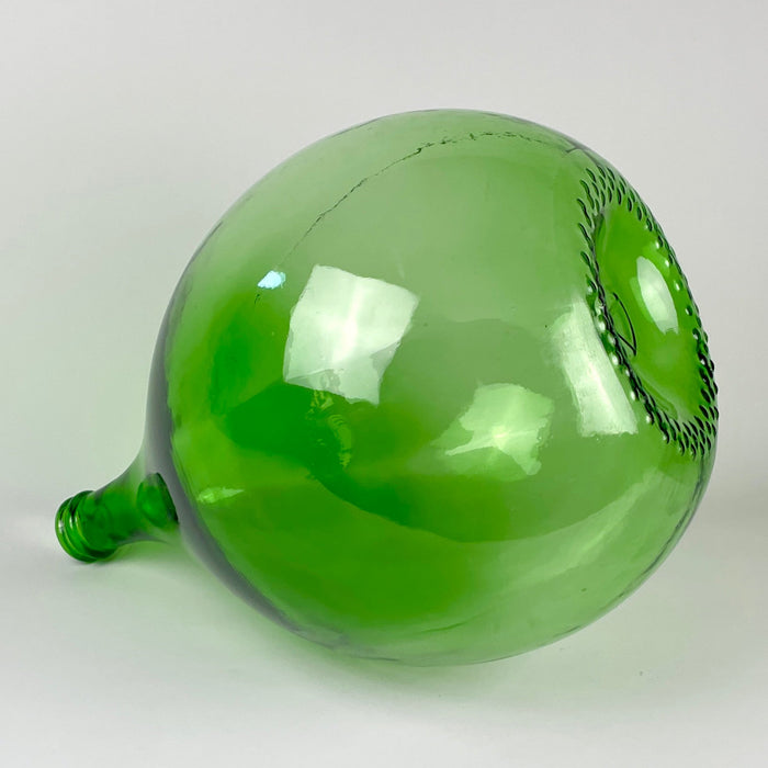 Large French green glass wine carboy with an organic teardrop silhouette, deep emerald color, translucent body, and visible bubbles, waviness, scratches, and manufacturing variations. The vintage demijohn has strong decorative scale and suits French country decor, Mediterranean decor, farmhouse decor, and collections of antique and vintage glass.