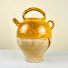 Ceramic jar with a yellowish-brown glaze. Antique French gargolette pottery jug from the 19th century featuring a rich yellow glaze over unglazed terracotta. Includes arched handle, side grip, and original lid, reflecting rural Figeac pottery tradition. Perfect for farmhouse decor, rustic home styling, and Mediterranean interiors.