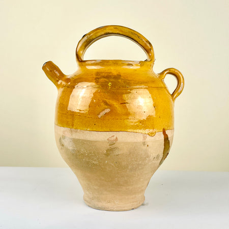 Ceramic jar with a yellowish-brown glaze. Antique French gargolette pottery jug from the 19th century featuring a rich yellow glaze over unglazed terracotta. Includes arched handle, side grip, and original lid, reflecting rural Figeac pottery tradition. Perfect for farmhouse decor, rustic home styling, and Mediterranean interiors.