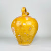 Reverse view of a large antique French cruche pot from Provence, showing the strongly curved earthenware body and sculptural overhead handle. Honey-yellow glaze, extensive areas of rose terracotta and pale mineral deposits create a richly weathered pottery surface for collected Mediterranean decor.