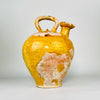 Very rare Provençal pottery water jug shown from the opposite side, with a substantial terracotta body, small circular foot and raised yellow-glazed pouring mouth. Extensive historic glaze loss reveals warm rose clay beneath, giving the antique French cruche a dramatic surface suitable for rustic home decor.