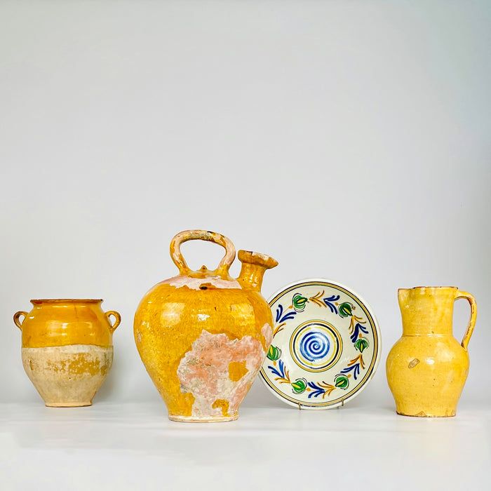 Antique Provençal cruche displayed beside other yellow-glazed pottery and a hand-painted ceramic bowl, illustrating how the large 38 cm water jug works within a collected arrangement. Its mustard glaze, rare spout and exposed terracotta complement layered French country decor and natural textiles.