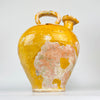 rare French pottery water jug with a large pinched pouring mouth positioned beside a thick overhead handle. The closed terracotta shoulder retains areas of mustard glaze, fine crazing and historic surface wear, distinguishing the vessel from more commonly encountered narrow-necked gargoulettes.