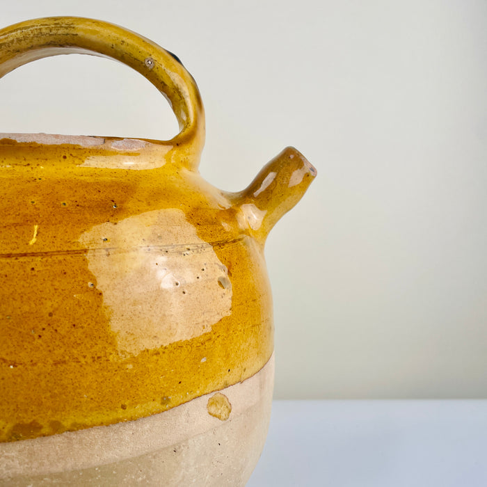 Yellow ceramic pot with a handle. Detail of glaze surface on the French pottery jug, showing authentic craquelure and aged terracotta texture. Ideal for wabi-sabi collectors and organic modern interiors that value handcrafted imperfection.