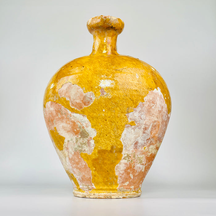 rare pinched spout on a large French gargoulette water jug. The wide asymmetric rim retains mustard-yellow glaze, firing speckles and natural wear, while small edge losses and exposed rose clay reveal the handmade construction of this unusual Provence terracotta vessel.