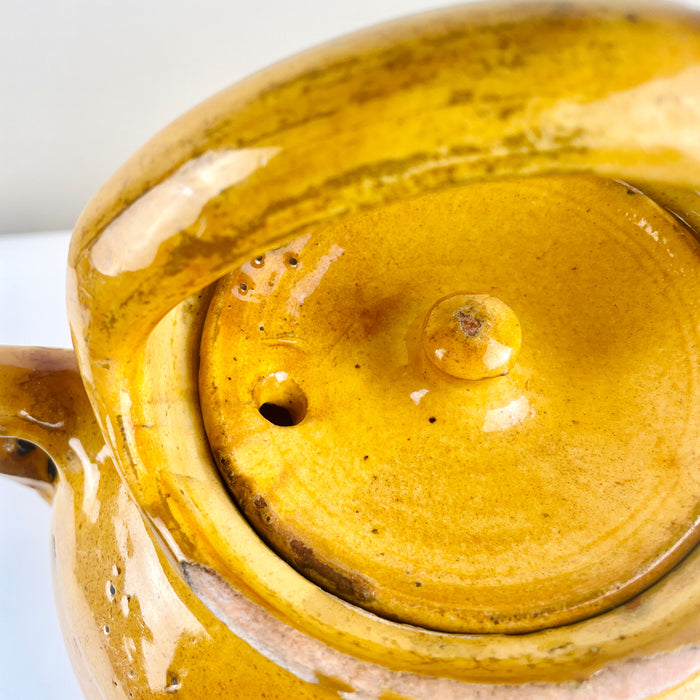 Top-down view showing original lid and arched handle of antique French water jug. The yellow glaze and irregular surface highlight its handmade 19th-century craftsmanship, suited for farmhouse kitchens and Mediterranean rustic interiors.