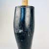 Antique French mannequin leg standing on its carved boot and heel, with the long calf rising to an original wooden mounting dowel and metal retaining pin. The deep black finish is mottled by scratches, rubbed patches and exposed timber from decades of handling. Its period form is especially compatible with Napoleon III decor.