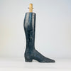 This single surviving leg from a set of antique French mannequin legs stands independently on its carved boot and heel. Heavy solid wood, worn black paint, a tapered calf, long toe and exposed upper attachment dowel identify its former function as part of a tailor’s display figure. Its vertical sculptural form works naturally as distinctive bookshelf decor.