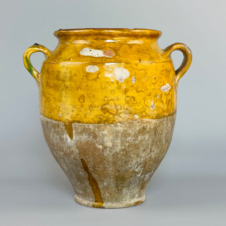 Antique French confit jar with yellow and green glaze, two side handles, and unglazed base, used in Southwest France during the 19th century for preserving duck or olives. Terracotta patina and firing marks reflect rustic farmhouse authenticity.