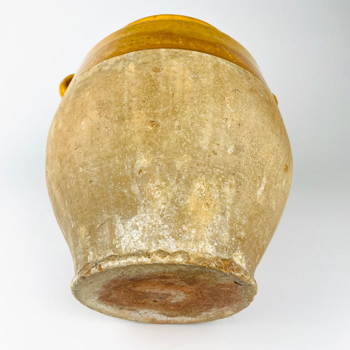 Antique French pottery confit pot with a rounded body, paired ear handles and partial ochre glaze, suitable as a decorative cachepot when used with a protective liner. The matte lower terracotta, worn rim and aged glaze give the vessel a strong wabi sabi decor presence.