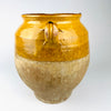 Antique French confit jar showing naturally flowing ochre glaze descending from the shoulder onto the unglazed terracotta body. The thick drip, wheel marks, abrasions and pale mineral surface are integral to this 19th century pottery vessel and give it distinctive vintage kitchen decor appeal.