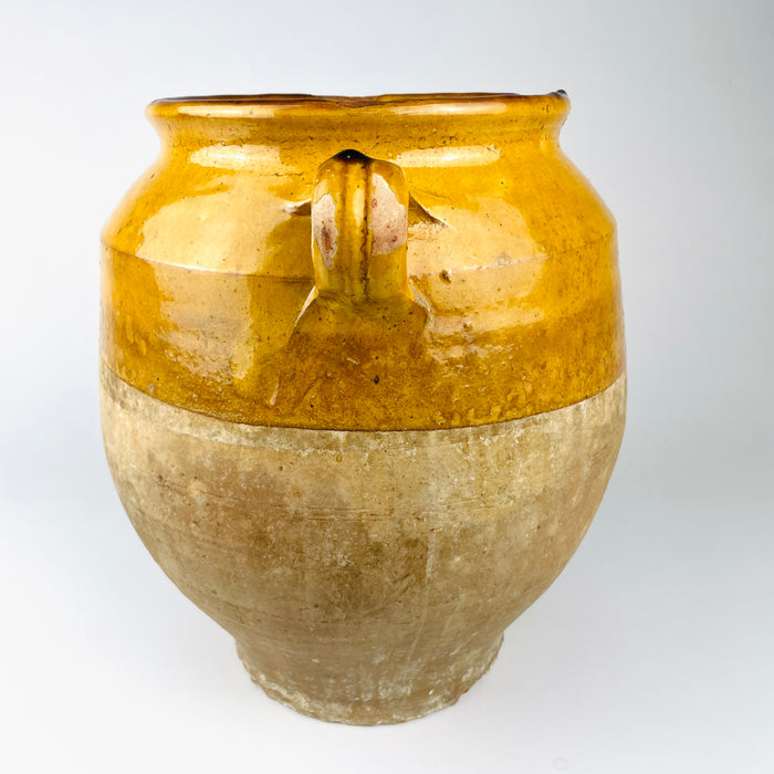 Antique French confit jar showing naturally flowing ochre glaze descending from the shoulder onto the unglazed terracotta body. The thick drip, wheel marks, abrasions and pale mineral surface are integral to this 19th century pottery vessel and give it distinctive vintage kitchen decor appeal.