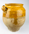 late 19th century French terracotta confit jar with a bulbous body, flared rim and two small ear handles. Honey and ochre glaze covers the shoulder while the lower clay remains matte and weathered, giving this functional food preserving pot strong rustic home decor character.