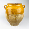 Large antique French confit pot from the late 19th century, hand thrown in terracotta with a mustard yellow glazed upper body, fully glazed interior, wide rolled rim and two loop handles. The rounded preserving jar narrows to a footed base, combining authentic French pottery with French country decor.