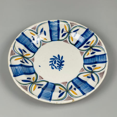 Hand-painted Manises plate, white ceramic base with radial cobalt floral motif and striped rim design, presented on a stand, suitable for Spanish farmhouse interiors.