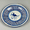 Spanish faience wall plate from Manises, featuring hand-painted bird at center and bold radial geometric design, in white and deep cobalt glaze, photographed on neutral grey background.