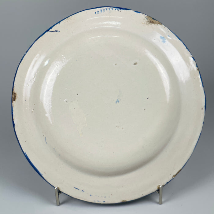 Underside angle of antique Spanish ceramic wall plate, showing tin glaze finish and brass wall hanging fixture, suitable for display in collector or Mediterranean decor context.