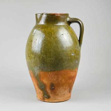 Large 19th-century Spanish clay jug with single handle and pinched spout, captured at three-quarter angle to emphasize curved profile, traditional glaze finish, and hand-thrown construction ideal for rustic pottery collectors.