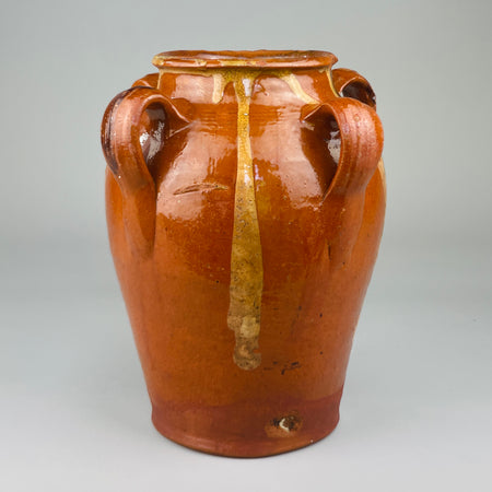 Red clay vessel from Toledo, Spain with looped handles and irregular glaze drips, viewed head-on to highlight handmade form, decorative surface, and traditional firing characteristics, ideal for rustic home decor or ceramic collectors.