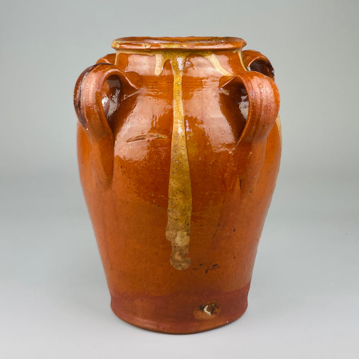 Red clay vessel from Toledo, Spain with looped handles and irregular glaze drips, viewed head-on to highlight handmade form, decorative surface, and traditional firing characteristics, ideal for rustic home decor or ceramic collectors.