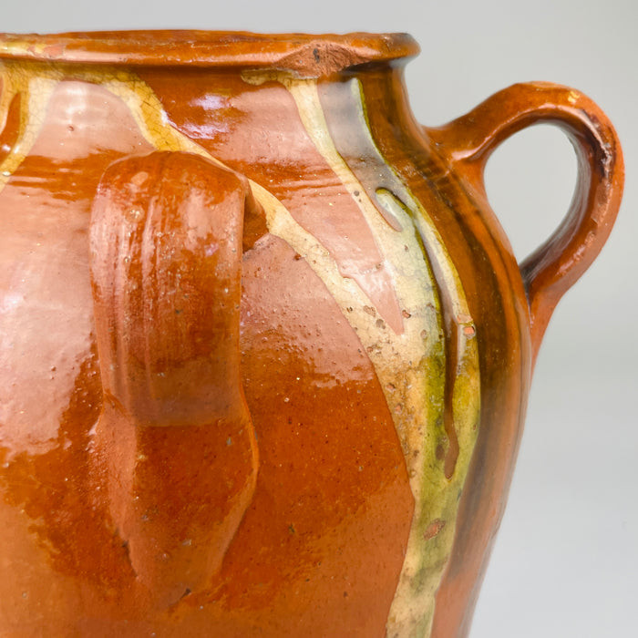 Green-glazed drip trail down terracotta surface draws eye vertically along jar’s form, perfect for rustic ceramic photography focused on texture and design features in Mediterranean or farmhouse spaces.