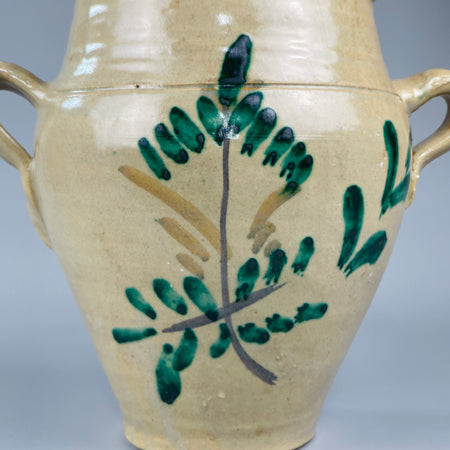 Front-facing view of vintage Lucena orza jar with symmetrical curved form, green brushwork decoration and scrolled handles, showcasing traditional Andalusian ceramic artistry and rustic Southern Spanish design from the early 20th century.