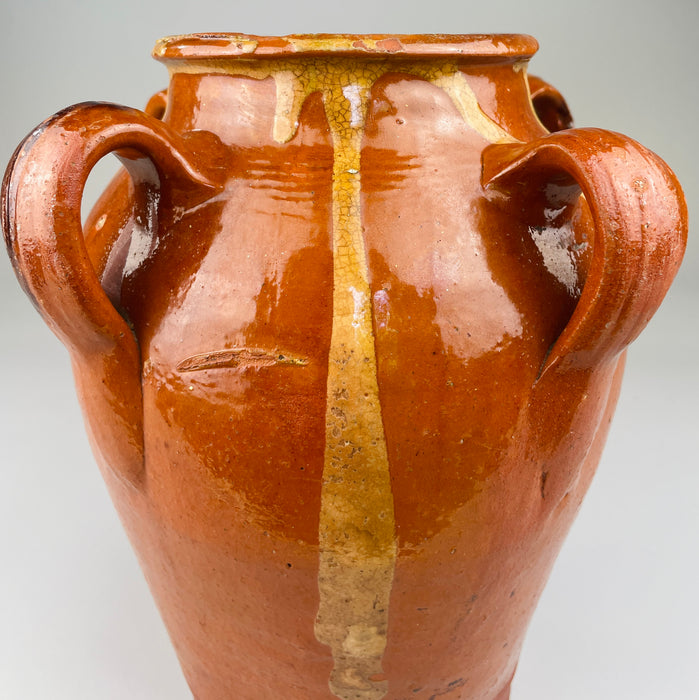 Red clay vessel from Toledo, Spain with looped handles and irregular glaze drips, viewed head-on to highlight handmade form, decorative surface, and traditional firing characteristics, ideal for rustic home decor or ceramic collectors.