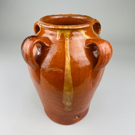 Antique Spanish terracotta jar with four handles and vertical glaze drips in green and yellow, photographed upright on neutral background, representing early 20th-century Toledo pottery traditions and rustic Mediterranean design.
