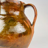 Hand applied loop handle on an antique Spanish orza jar, showing the joined clay construction, worn glaze and natural variations around the attachment point. The red earthenware body and amber brown glazed finish are characteristic of rural utilitarian pottery, making the vessel suitable for Mediterranean decor and rustic home decor.