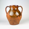 Wheel thrown Spanish terracotta vase displaying horizontal turning lines beneath the amber brown glaze and subtle hand formed irregularities throughout the body. The two handled Castilian orza jar dates to the nineteenth century and combines utilitarian pottery construction with an expressive aged surface for antique and vintage home decor.