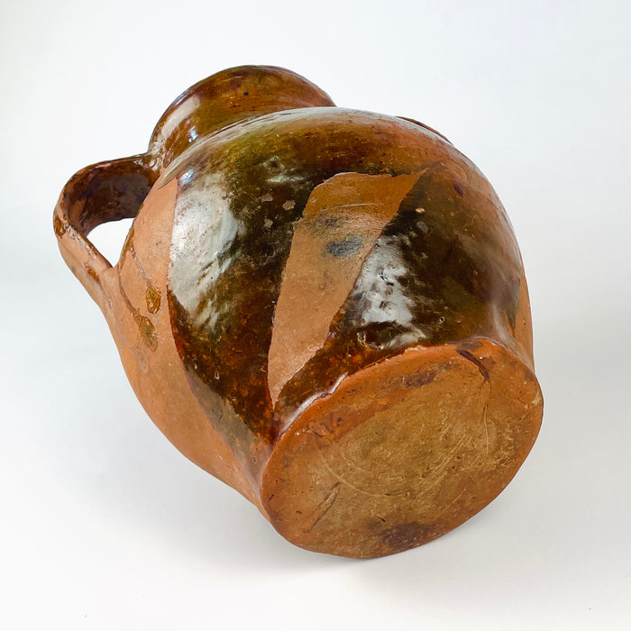 Base detail of an antique Spanish glazed terracotta orza jar, showing the flat circular foot, concentric wheel thrown lines and natural red clay surface. The utilitarian Castilian pottery construction supports its identity as a nineteenth century storage vessel, now suitable as a decorative vase for wabi sabi decor or rustic home decor.