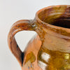 Nineteenth century Spanish terracotta vase measuring 24 cm tall, with a balanced two handled form, rounded shoulders and a flat base. The irregular amber and olive brown glaze flows across the upper red clay body while areas of exposed pottery create a graphic surface appropriate for Mediterranean decor, farmhouse decor and collected antique interiors.
